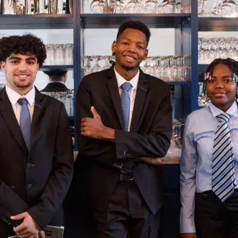 3 élèves devant le bar du restaurant